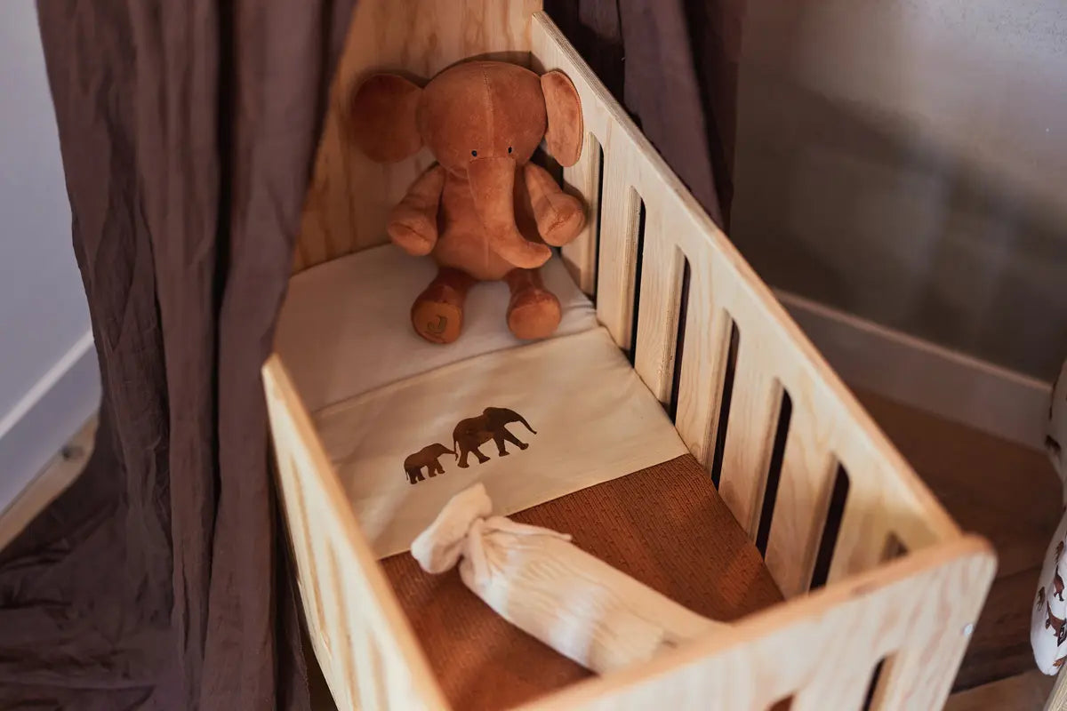 Ours en peluche de la marque Jollein dans un lit pour bébé